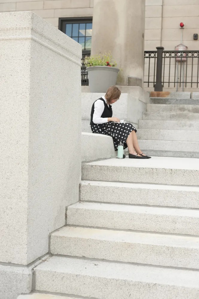 A woman sits on the steps of the Dedham courthouse