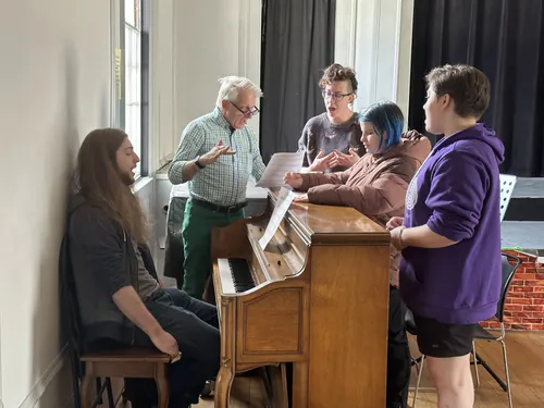 A group gathers around a piano to sing together