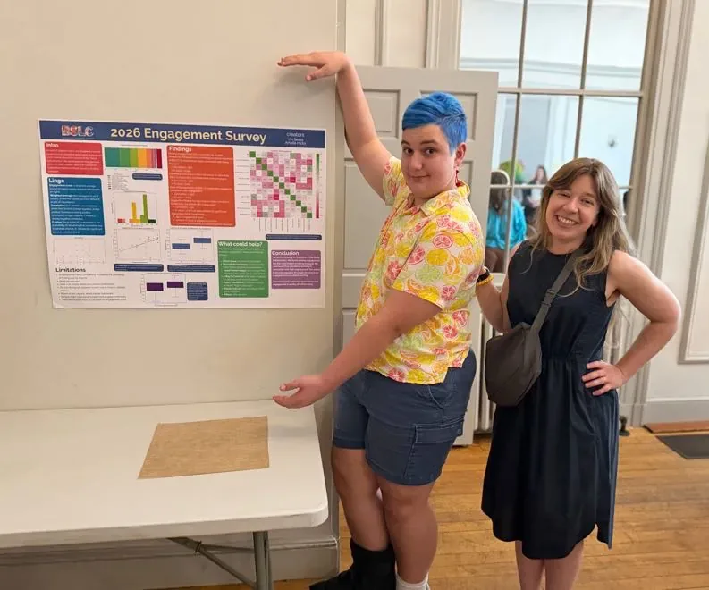 Vin and Amelia stand next to Vin's research poster, presenting his findings on engagement.
