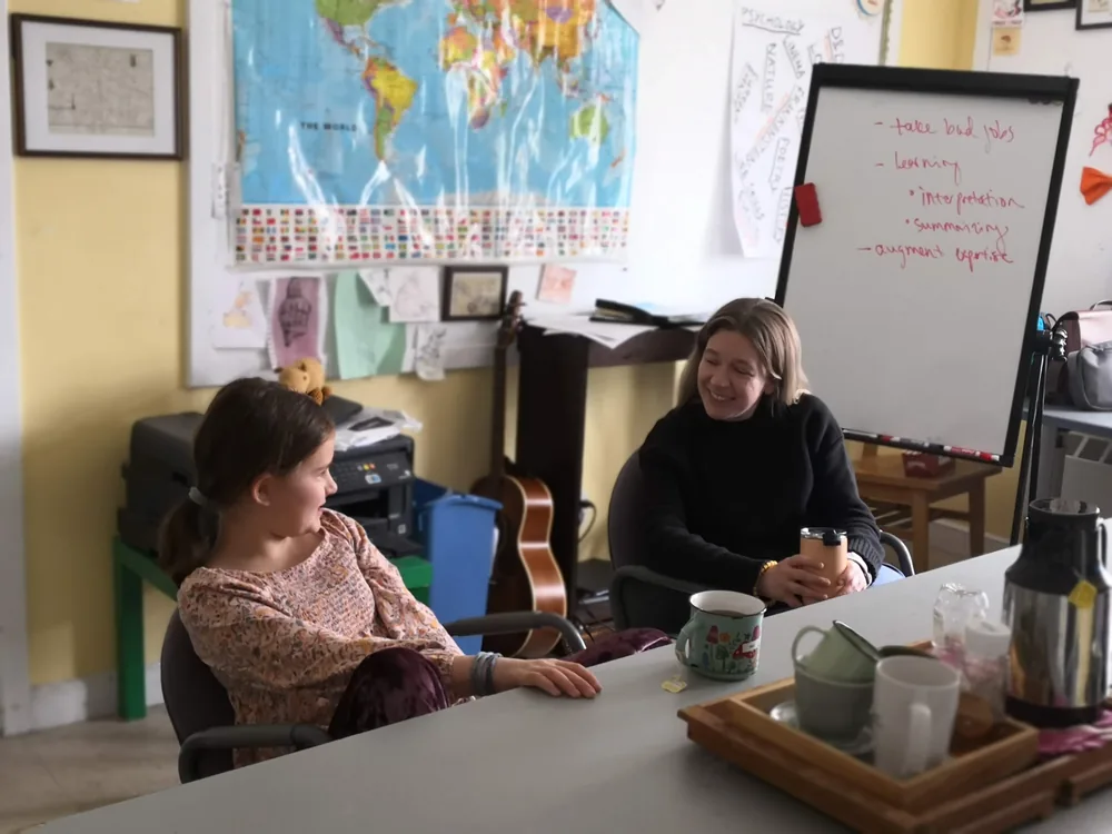 A staff member and BSLC member drink tea together during a mentoring meeting.