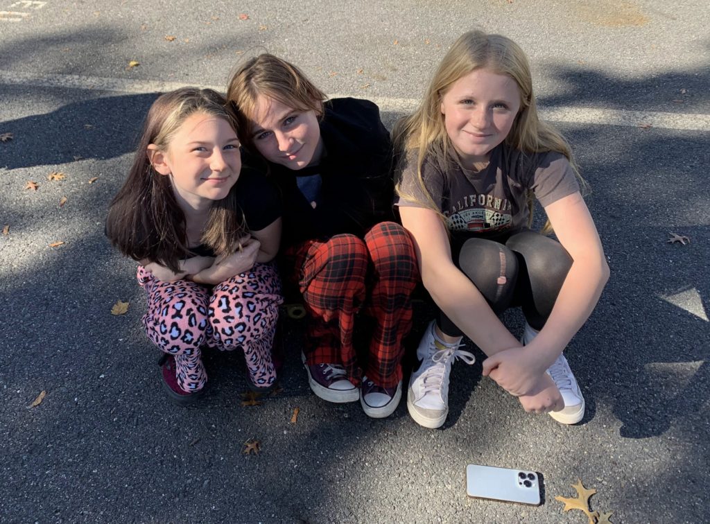 Three students smiling and sitting together outside